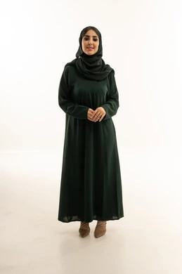 امرأة سعودية بعباية خضراء على خلفية بيضاء