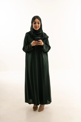 امرأة سعودية بالعباءة الخضراء تستخدم الجوال في الاستوديو