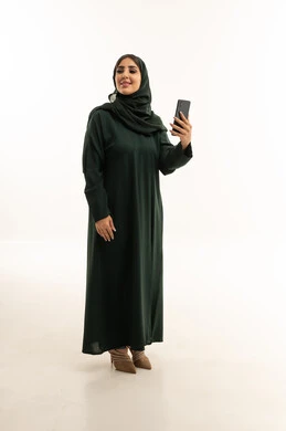 امرأة سعودية بعباءة خضراء تستخدم هاتف ذكي