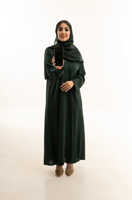 امرأة عربية بالعباءة تمسك هاتف محمول بشاشة فارغة