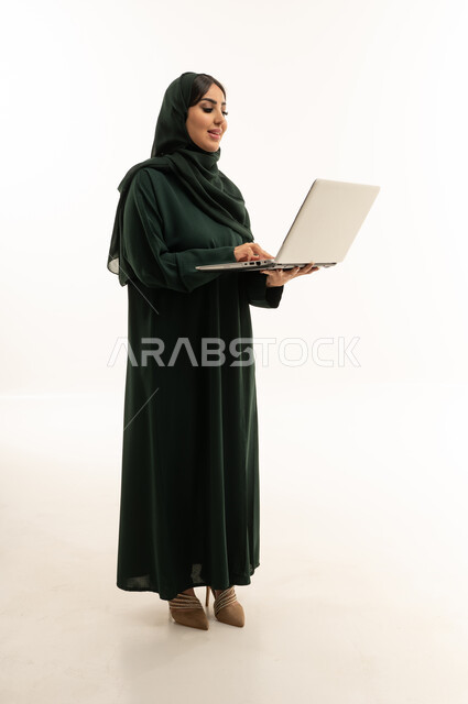 امرأة سعودية بعباية خضراء تستخدم اللابتوب في الاستوديو