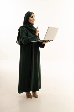امرأة سعودية بعباءة خضراء تستخدم الكمبيوتر المحمول
