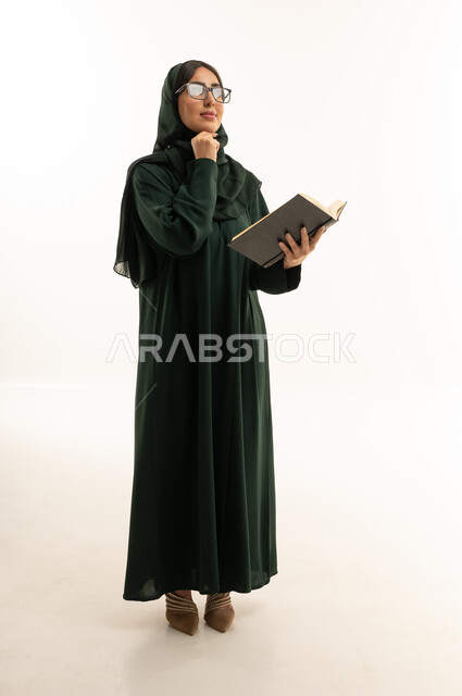 امرأة عربية بعباية خضراء تفكر وتمسك كتابا في استوديو