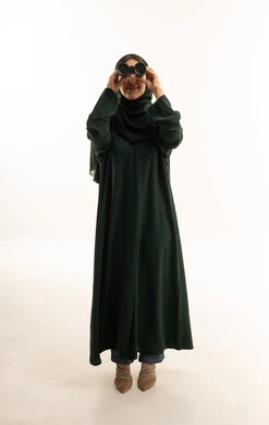 امرأة سعودية بعباءة خضراء تستخدم المنظار في الاستوديو