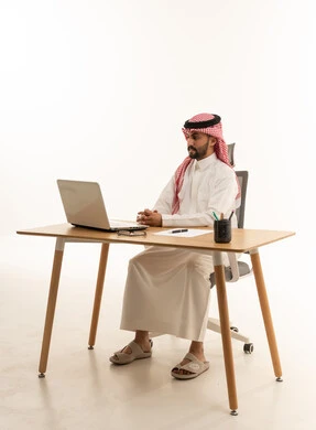 رجل أعمال سعودي على مكتب مع كمبيوتر محمول