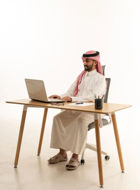 Saudi Man Working on Laptop at Desk White Background