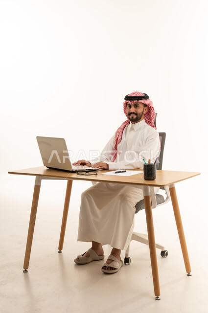 Saudi Businessman Using Laptop at Desk White Background