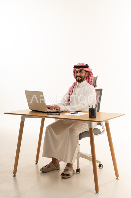 رجل أعمال سعودي يستخدم اللابتوب على مكتب العمل