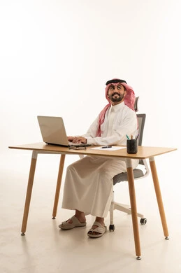 رجل سعودي يعمل على جهاز كمبيوتر محمول في مكتبه
