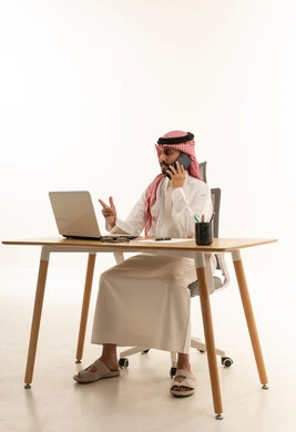 Saudi Businessman Working at Desk with Laptop and Phone