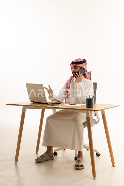 Saudi Businessman at Desk with Laptop and Phone