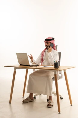 Saudi Businessman at Desk with Laptop and Phone
