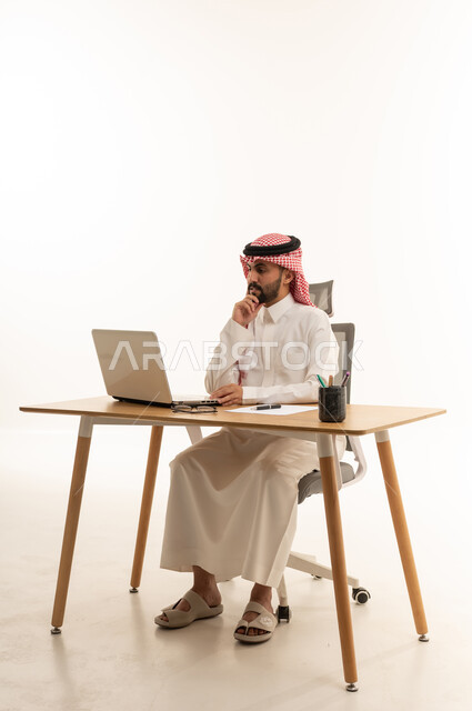 Saudi Businessman Using Laptop at Office Desk