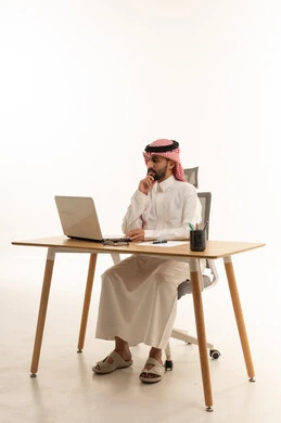 Saudi Businessman Using Laptop at Office Desk