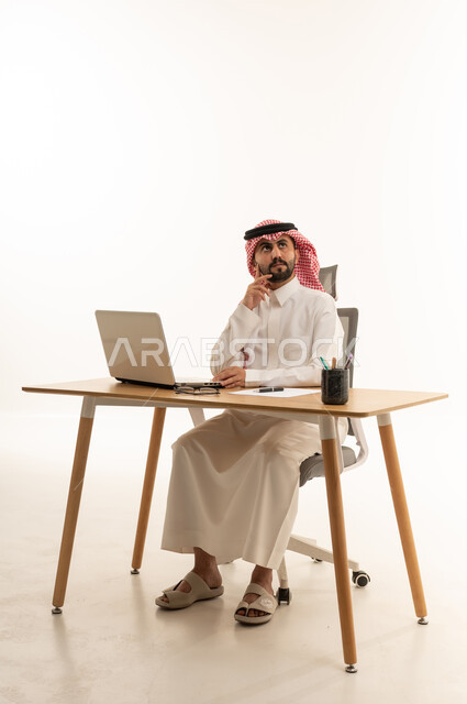 Saudi Businessman Thinking at Desk with Laptop