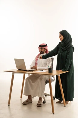 زملاء عمل سعوديون يعملون على كمبيوتر محمول