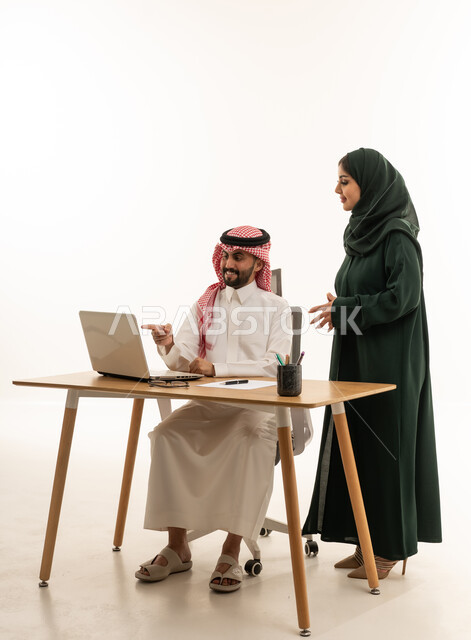 زملاء عمل سعوديون يعملون على كمبيوتر محمول في مكتب