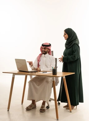 زملاء عمل سعوديون يعملون على كمبيوتر محمول في مكتب