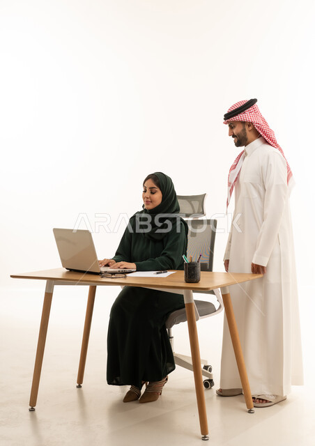 زملاء عمل سعوديون يعملون على كمبيوتر محمول
