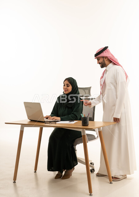 زملاء عمل سعوديون يعملون على كمبيوتر محمول في المكتب