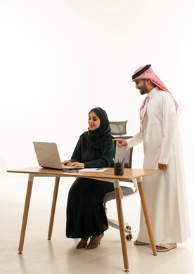 زملاء عمل سعوديون يعملون على كمبيوتر محمول في المكتب