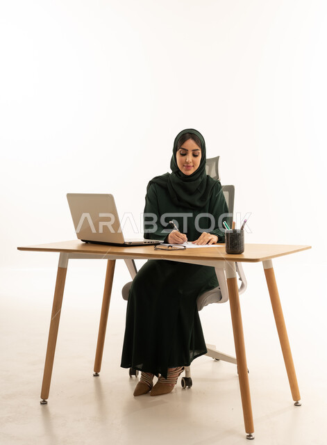سيدة أعمال سعودية تكتب على المكتب مع لابتوب