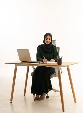 سيدة أعمال سعودية تكتب على المكتب مع لابتوب