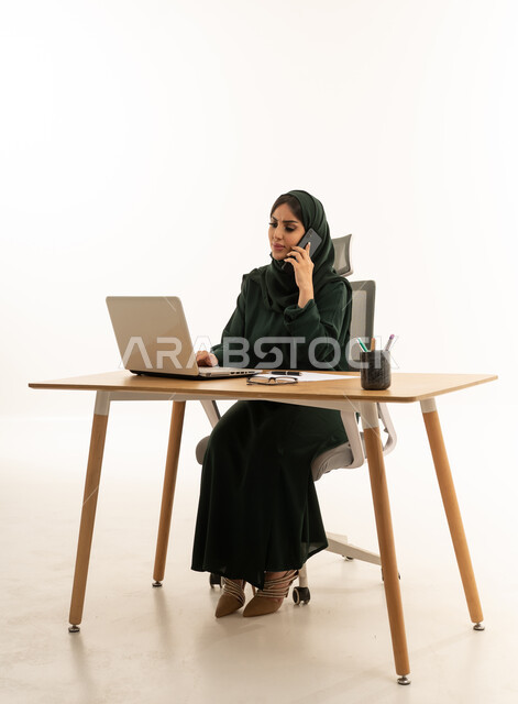 سيدة أعمال سعودية تتحدث بالهاتف على مكتب العمل