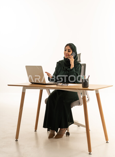 سيدة أعمال سعودية تعمل على المكتب مع لابتوب وهاتف