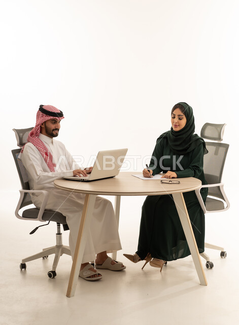رجل وسيدة أعمال سعوديان يعملان في استوديو أبيض