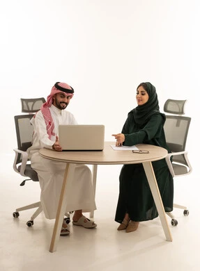 رجل وسيدة أعمال سعوديين يعملان على جهاز محمول