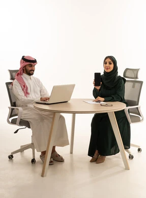 محترفون سعوديون مع لابتوب وهاتف ذكي في المكتب