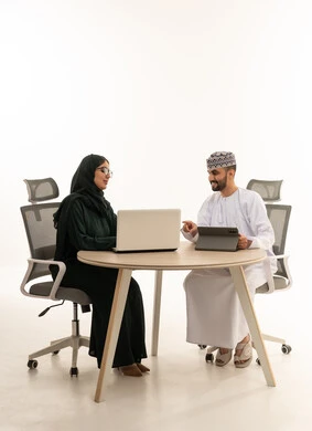 رجال أعمال عمانيون يعملون على الحاسوب والجهاز اللوحي