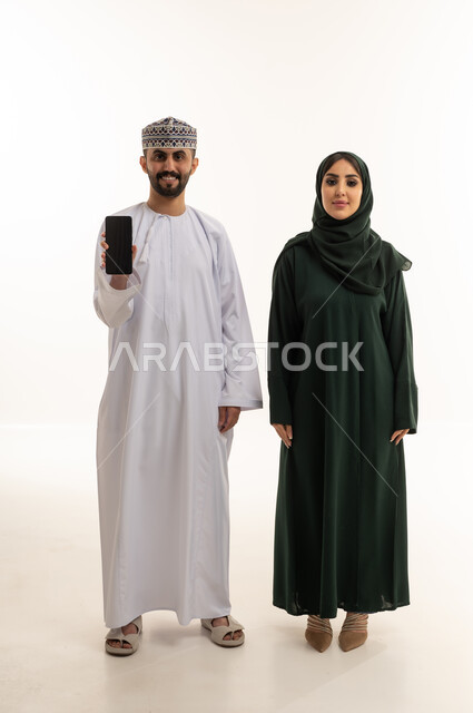 زوجين عُمانيين مع هاتف ذكي على خلفية بيضاء