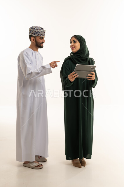 رجل وامرأة من عمان يستخدمان جهاز لوحي خلفية بيضاء