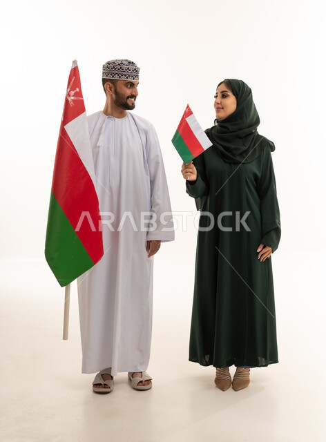 رجل وامرأة عمانيان يحملان علم عمان في الاستوديو