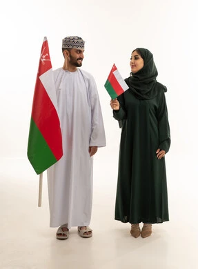 رجل وامرأة عمانيان يحملان علم عمان في الاستوديو
