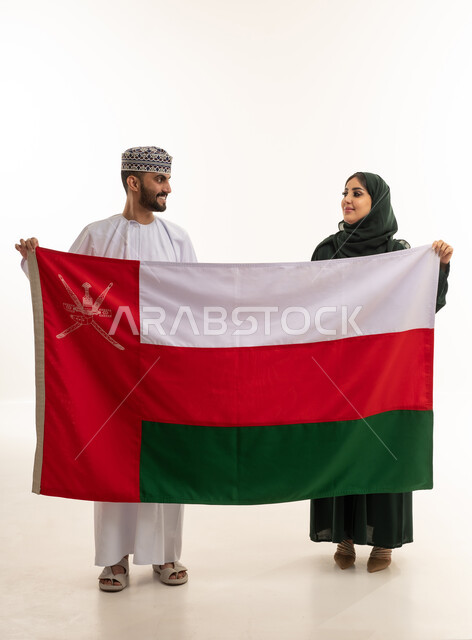 رجل وامرأة عمانيان يحملان علم سلطنة عمان
