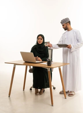 زملاء عمل عمانيون يعملون على كمبيوتر محمول في الاستوديو