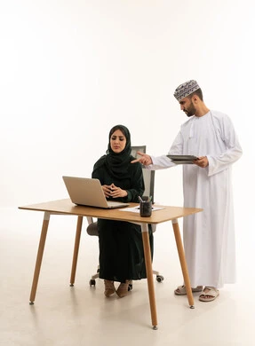 زملاء عمل عمانيون يعملون على جهاز المحمول في المكتب