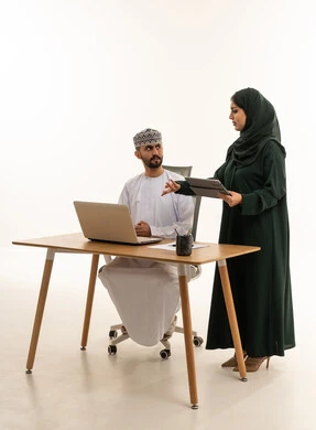 مهنيون عمانيون يناقشون العمل مع كمبيوتر محمول وجهاز لوحي