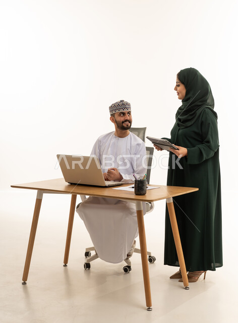 موظفون عُمانيون يعملون مع كمبيوتر محمول وجهاز لوحي