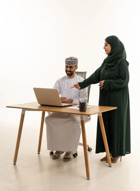 زملاء عمل عُمانيون يعملون على جهاز كمبيوتر