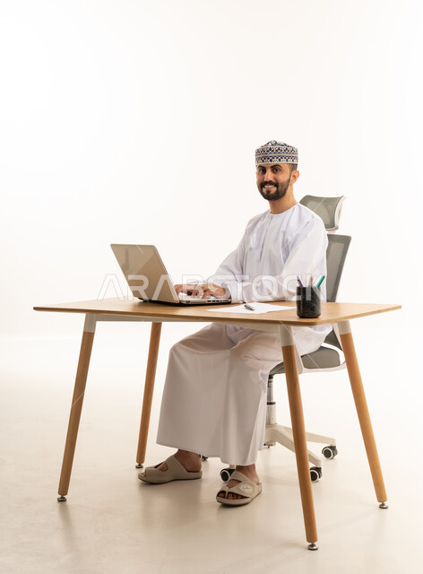 Omani Businessman Using Laptop at Desk on White Background