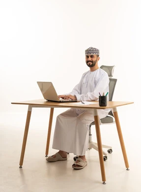 Omani Businessman Using Laptop at Desk on White Background