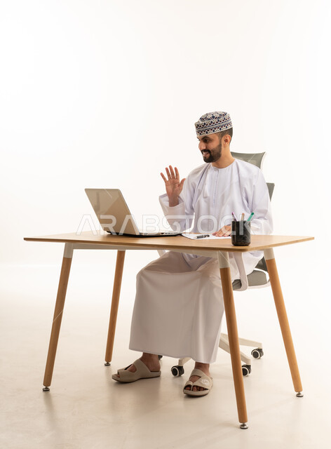 رجل عُماني يلوح للحاسوب في مكتب استوديو