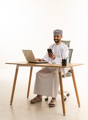 رجل أعمال عماني يستخدم المحمول والهاتف في المكتب