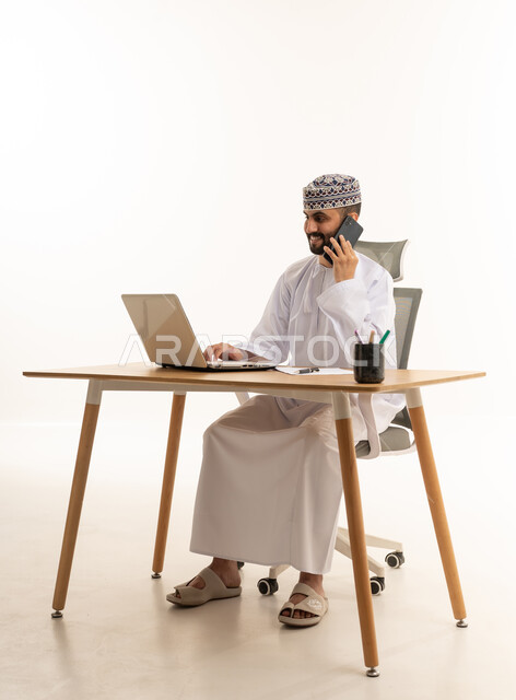 Omani Man Working on Laptop and Calling in Office