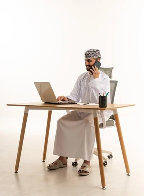 رجل أعمال عماني يعمل على اللابتوب ويتصل بالمكتب