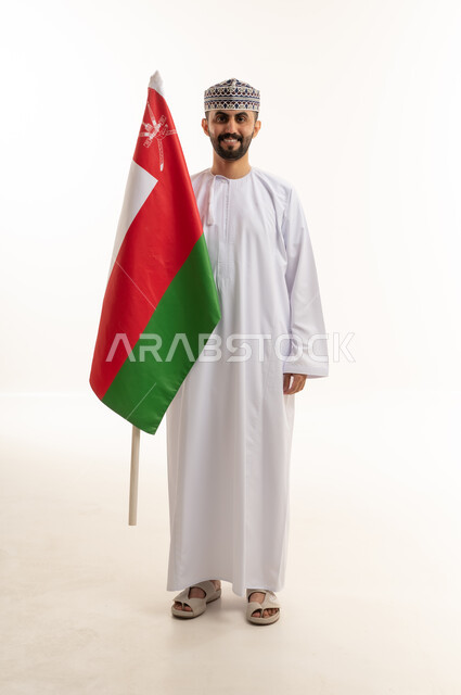 رجل عماني يقف مع علم سلطنة عمان الوطني